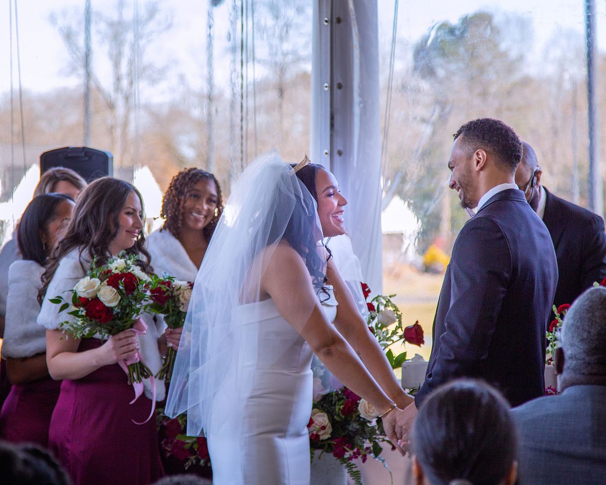 bride and groom during wedding ceremony, holding hands and smiling at each other