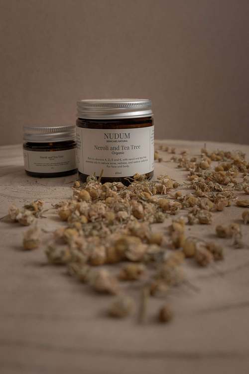 Glass jar product photographed with scattered oats on a neutral surface