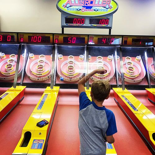A boy playing skeet ball at an arcade