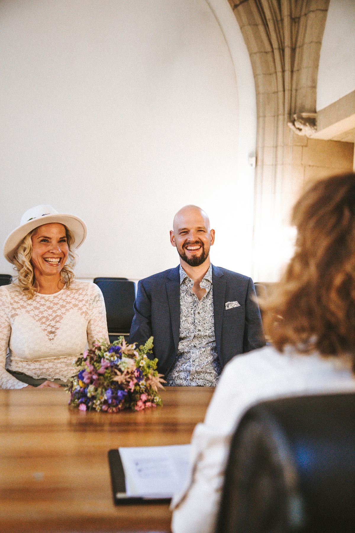 Brautpaar sitzt auf der Bank im Trausaal w&auml;hrend der standesamtlichen Trauung, emotionale Hochzeitsfotografie in K&ouml;ln.