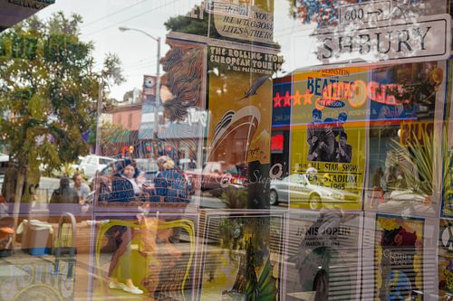 Reflections of the Haight-Ashbury neighborhood, featuring Beatles and Grateful Dead posters in a storefront, highlighting cultural identities in San Francisco.