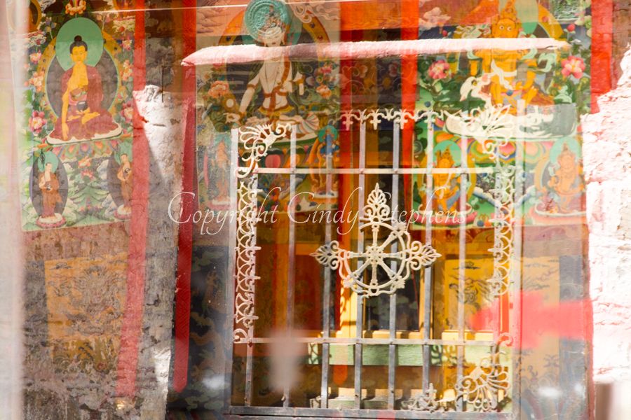 Colorful Tibetan symbolism as reflected in shop window with grate in background